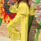 Woman posing in a yellow sweatsuit outfit posing in front of a colorful mural.
